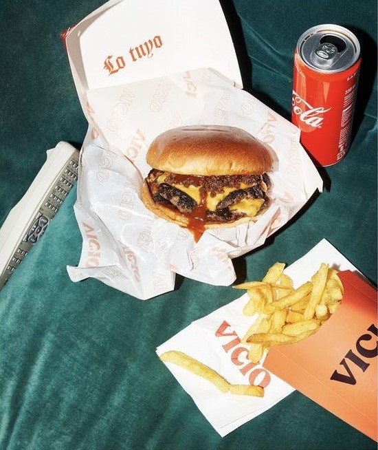 Hamburguer com batata frita e refrigerante em cima de uma cama